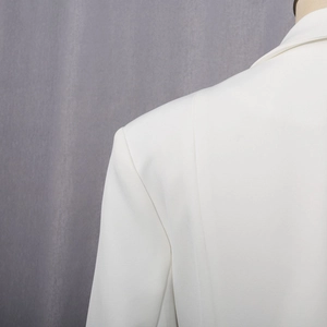 Detailed view of white blazer shoulder tailoring and clean lapel edge stitching