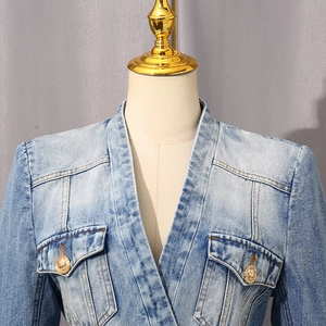 Detailed macro of a light blue washed denim jacket with gold lion-head buttons and V-neckline