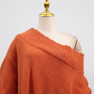 Detail of orange chunky knit sweater with asymmetrical off-shoulder rib neckline