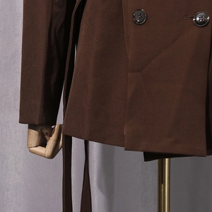 Detailed view of dark brown double-breasted blazer with matching buttons and waist belt