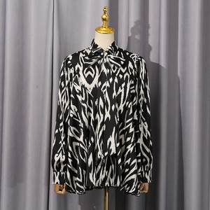 Detail of a silky long-sleeve blouse with abstract black and white wave print and bow tie neck