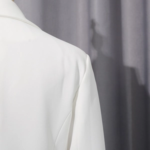 Détail de l'épaule d'un blazer blanc avec épaulettes structurées et coutures de qualité