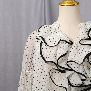 Detail of ruffle collar and black contrast edging on a white polka dot chiffon blouse