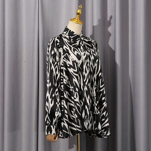 Detail of black and white geometric print shirt with tied stand collar and smooth texture