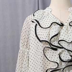 Detail of ruffled collar with black trim on white polka dot chiffon blouse sleeve
