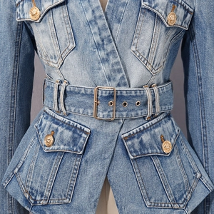 Detailed view of denim jacket with golden lion embossed buttons and belted waist accent
