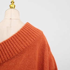 Detail of orange knitted sweater showing ribbed neckline texture and soft fabric finish