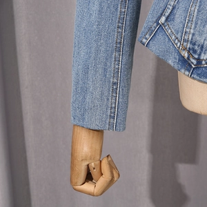 Detail view of light blue denim jacket sleeve with precise stitching on high-quality fabric