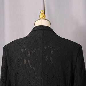 Detail of black floral lace texture and intricate hollow embroidery on a slim-fit blazer