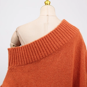 Detail of orange chunky knit off-shoulder sweater with ribbed neckline on a mannequin