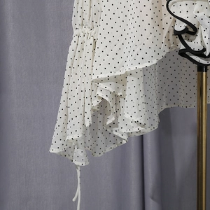 Detail of white chiffon shirt with black polka dots, ruffled edges and drawstring ties