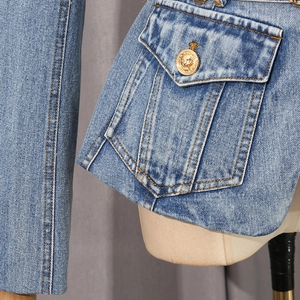 Detailed macro shot of blue denim jacket pocket with vintage gold lion head button
