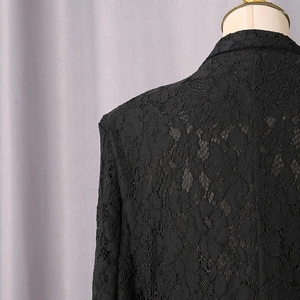 Close-up of intricate black floral lace pattern on woman's tailored suit blazer
