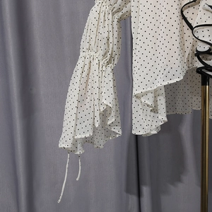 Detail of layered ruffle bell sleeves with black piping on white polka dot chiffon shirt