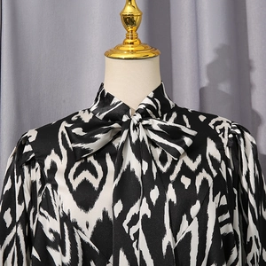 Detail of pussy-bow neckline and monochrome geometric print on satin blouse