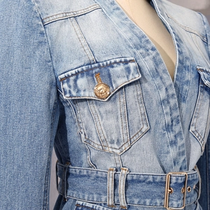 Detail of light blue denim jacket with padded shoulders and lion head gold button