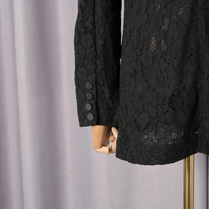 Detailed view of floral lace texture and four decorative buttons on blazer sleeves