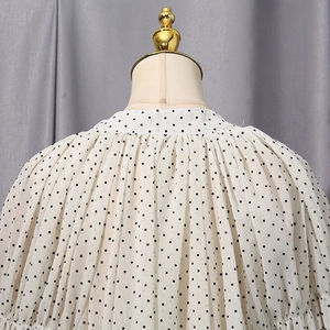 Close-up of white chiffon blouse with black polka dots and ruffled shoulder details