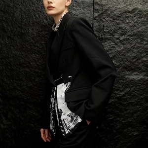 Detail of slim-fit black blazer with white contrast artistic print and silver chain