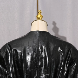 Détail macro d'une veste en similicuir noir avec gaufrage crocodile et fini brillant