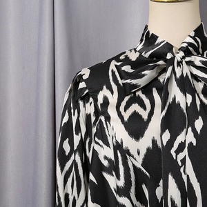 Detailed view of women's black and white abstract shirt with tie-up bow neckline