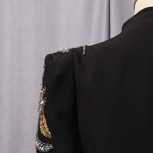 Detail of heavy beadwork and rhinestones on the shoulder of a black tailored suit jacket