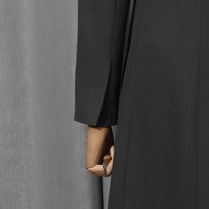 Close-up detail of the sleeve vent on a black minimalist women tailored suit jacket