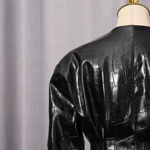 Détail de la veste noire en simili cuir à texture crocodile et doubles surpiqûres