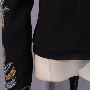 Macro detail of leaf-shaped sequin embroidery and beadwork on black blazer sleeves