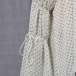 Detail of polka dot blouse sleeve with drawstring ties and elegant ruffle cuffs