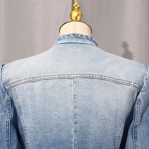Close-up of light blue washed denim jacket showing shoulder stitching and collar detail