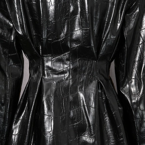 Détail de la texture croco noir brillant et de la taille cintrée sur un blazer