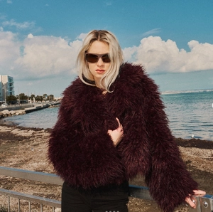 Detail of burgundy faux fur jacket showing plush texture and premium short cut design