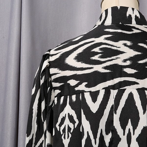 Detailed view of women's shirt featuring contrast geometric prints and satin finish fabric