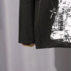 Detailed view of black blazer fabric featuring white cross and architectural print textures