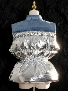 Gilet imbottito argento metallizzato con dettagli in denim su un manichino bianco