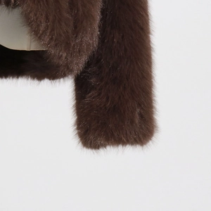 Close-up of deep brown faux fur texture with soft fluffy fibers on a stylish jacket