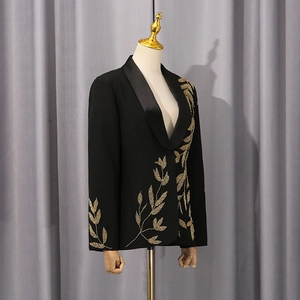 Détail d'un blazer noir avec broderies de feuilles dorées sur le col châle élégant