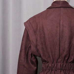 Detailed view of dark burgundy suede jacket featuring padded shoulders and cinched waist