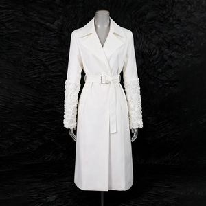 Vue détaillée du trench-coat blanc avec des fleurs 3D en relief sur les poignets