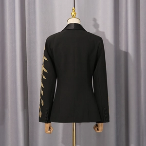 Détail de la broderie dorée sur manche de blazer noir avec boutons recouverts assortis