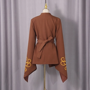 Detail view of terracotta blazer featuring floral embroidery on flared cuffs with a waist tie