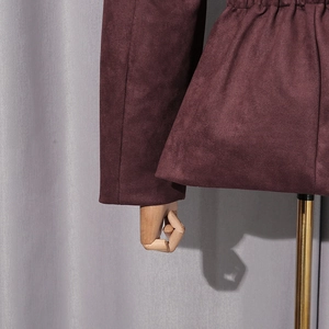 Detail of burgundy suede jacket featuring elastic waist pleats and smooth sleeve cuffs