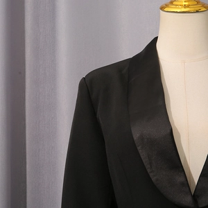 Détail d'un blazer noir avec revers en satin brillant et finition textile de qualité