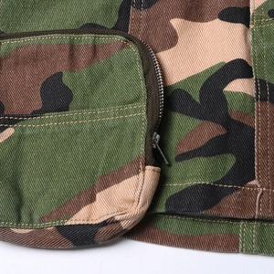 Detail of camouflage twill fabric featuring a metallic zipper pocket and precision stitching