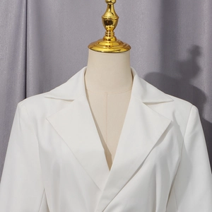 Détail d'un manteau blanc montrant le col à revers et la texture du tissu premium