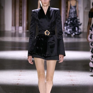 Détail d'un blazer en satin noir avec épaules structurées et ceinture à boucle dorée