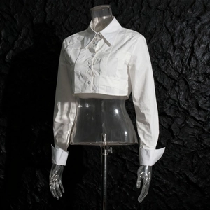 Dettaglio della camicia corta bianca con elegante trama a pieghe e bottoni frontali