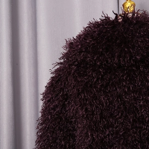 Close-up of deep burgundy faux fur jacket featuring curly texture and golden metallic detail