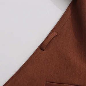 Macro shot of dark brown suit jacket waist detail showing belt loop and twill fabric texture